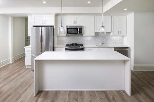 A kitchen with a white island and stainless steel appliances.