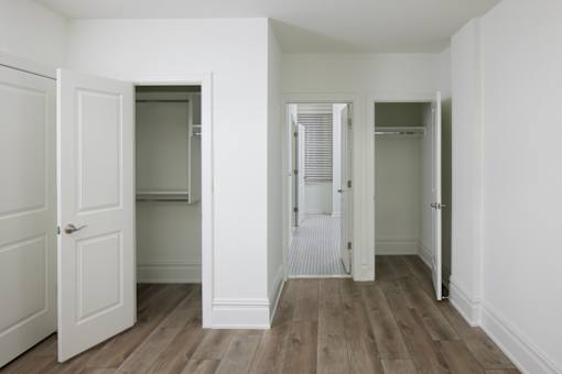 A room with white walls and wood flooring with three open doors.
