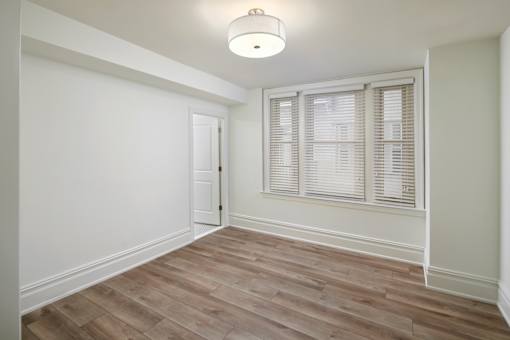 A room with a wooden floor and a window with blinds.