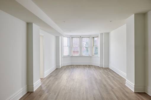A long, empty room with wooden floors and white walls.