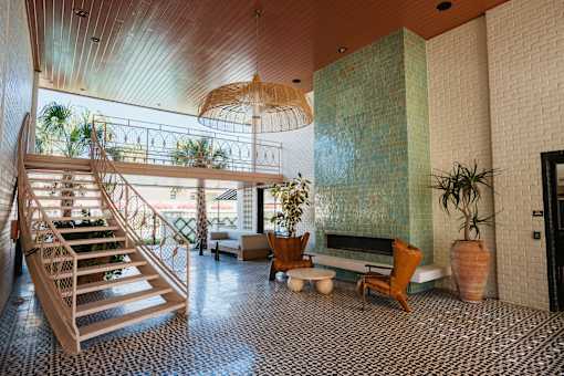 A wooden staircase with a glass railing leads to a balcony at The PARKER on E Mulberry Apartments, San Antonio, Texas