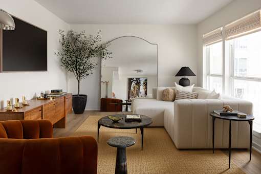 A living room with a white couch, a brown armchair, and a coffee table at The PARKER on E Mulberry Apartments, San Antonio, TX