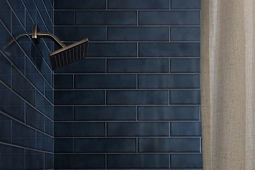 A black shower head mounted on a wall at The PARKER on E Mulberry Apartments, Texas