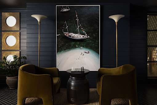 A room with a large picture of a boat on the wall and two yellow chairs at The PARKER on E Mulberry Apartments, San Antonio, Texas