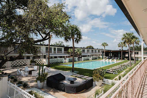 A pool area with lounge chairs and a white fence at The PARKER on E Mulberry Apartments, San Antonio, TX, 78209