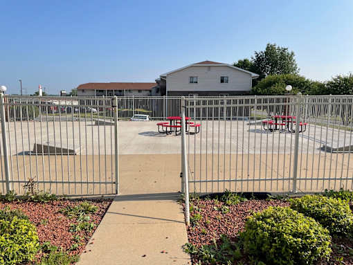 A fenced parking lot with a building in the background.
