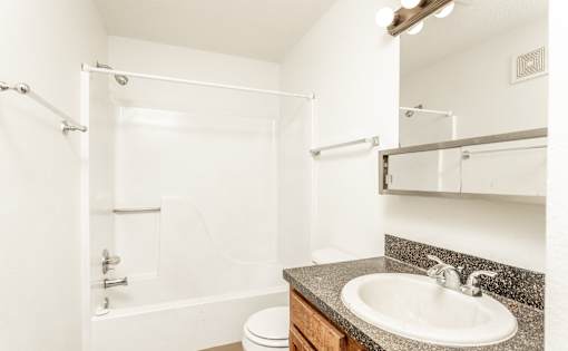 A white bathroom with a toilet, sink, and shower.