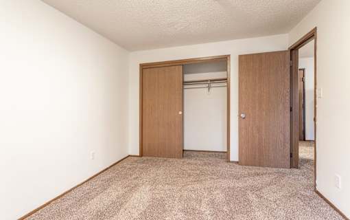 A room with a carpeted floor and two doors.