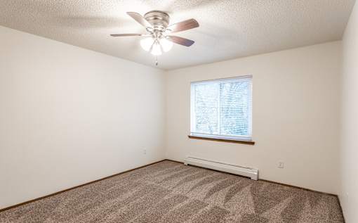a bedroom with white walls and a ceiling fan