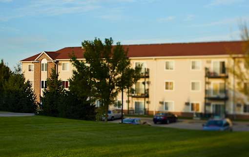 A large building with a red roof and a green lawn in front.