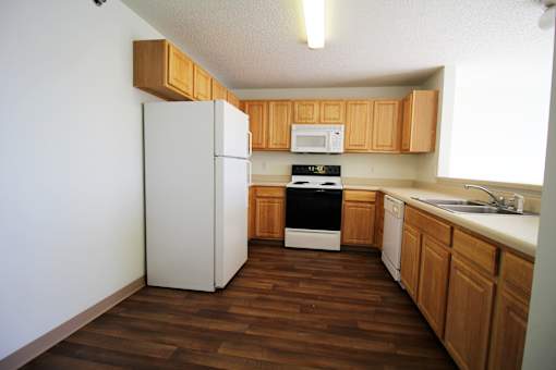 a kitchen with a white refrigerator freezer next to a stove top oven