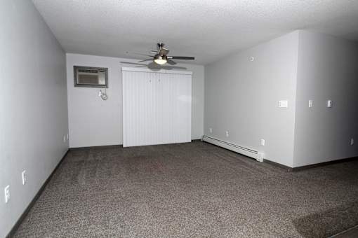 an empty living room with a ceiling fan