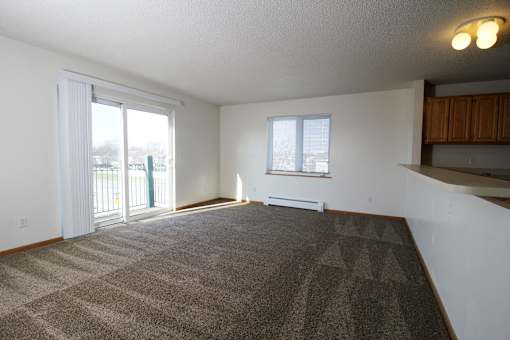 an empty living room with a sliding glass door and a balcony