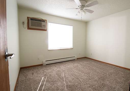 an empty room with a ceiling fan and a window