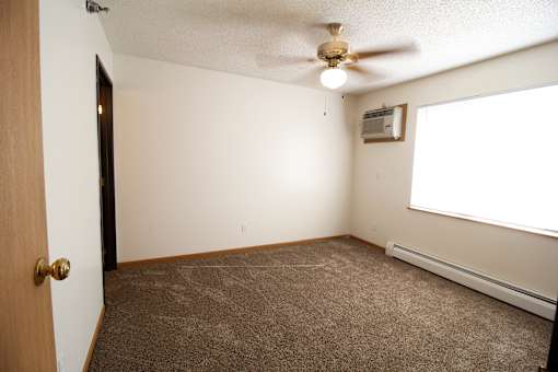 an empty room with a ceiling fan and a window