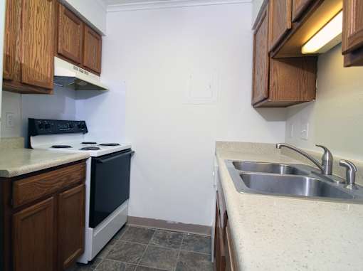 a kitchen with wooden cabinets and a white stove top oven