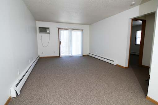 A room with a carpeted floor and a window with blinds.