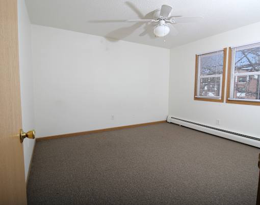 A room with a ceiling fan and carpeted floor.