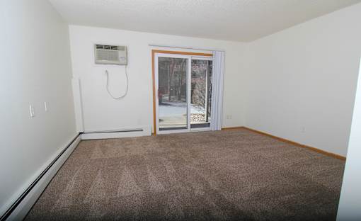 A room with a carpeted floor and a window with blinds.