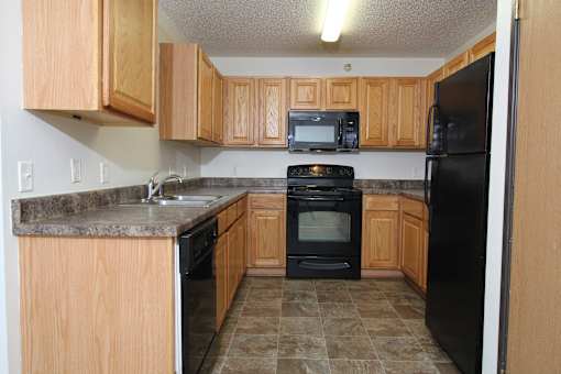 a kitchen with wood cabinets and black appliances