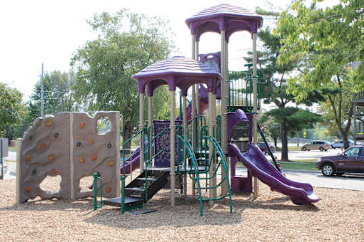 a playground with a rock climbing wall and slides