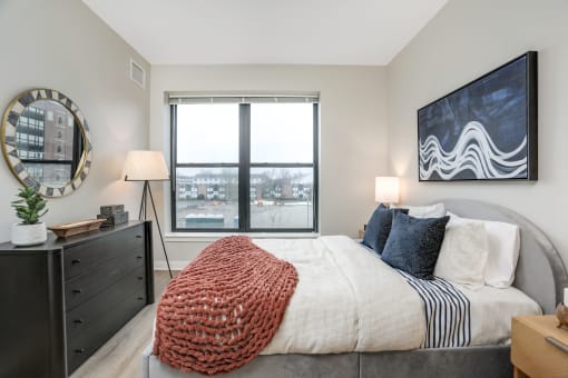 a bedroom with a large window and a bed with a blanket and pillows at Beekman on Broadway, Ann Arbor, MI