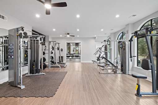 a home gym with exercise equipment and a ceiling fan
