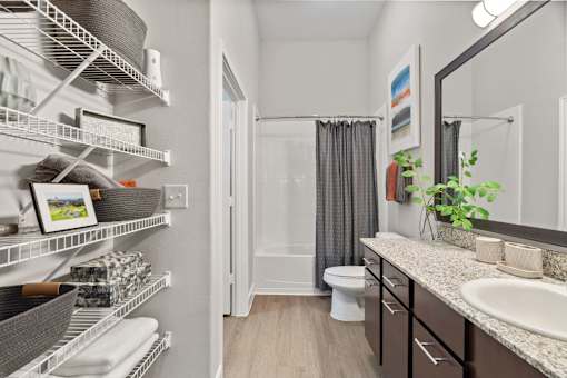 Bathroom with organized wire shelving and granite vanity at Urban Crest Apartments, San Antonio