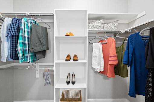 a walk in closet with shelves and clothes and shoes