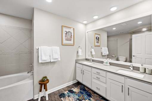 a bathroom with white cabinets and a large mirror and a tub