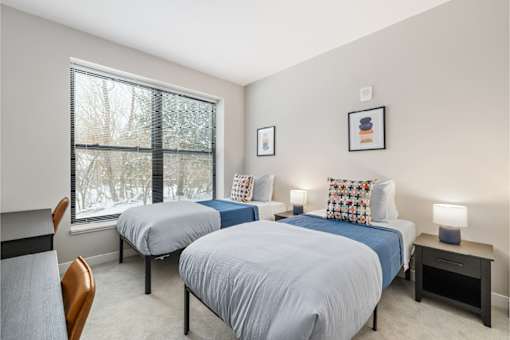 Two beds in a room with a window overlooking a snowy landscape.