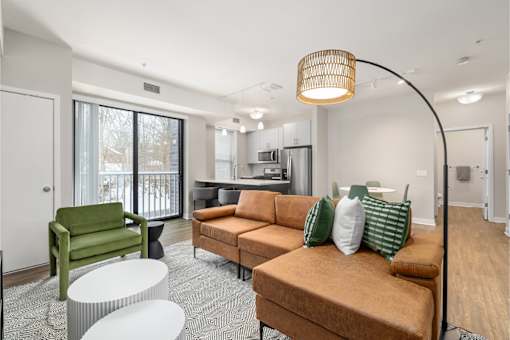 A living room with a green chair, a brown couch, and a white table.