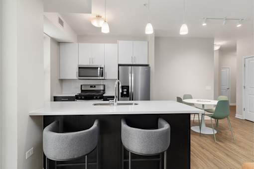 A modern kitchen with a white countertop and grey bar stools.
