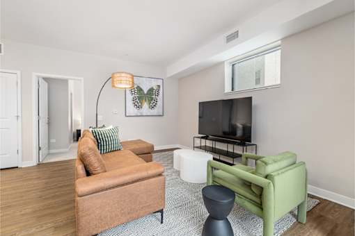A living room with a brown couch, a green chair, and a television.