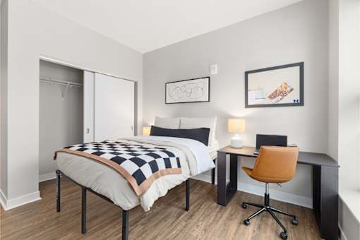 A bedroom with a bed, desk, and chair.