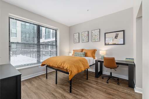 A bedroom with a bed, desk, and chair.