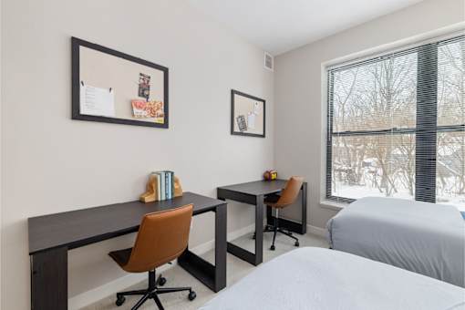A bedroom with a bed, desk, and chair.