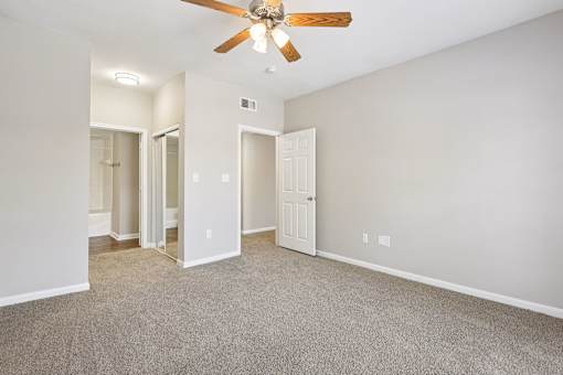 A room with a ceiling fan and carpeted floor.