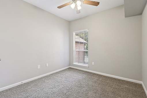 A room with a ceiling fan and a window with blinds.