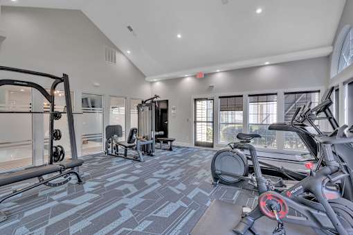 A spacious gym with a variety of equipment including treadmills, stationary bikes, and weight machines.