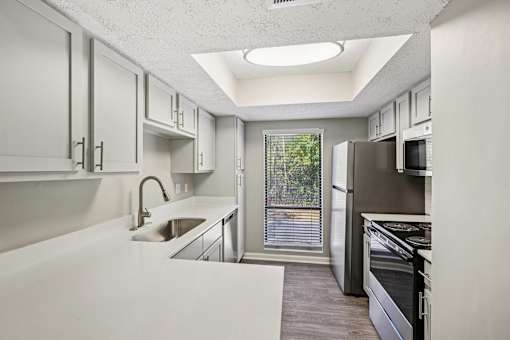 A modern kitchen with white cabinets and stainless steel appliances.