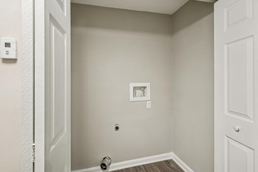 A white door is open to a small room with a light switch and a socket on the wall.