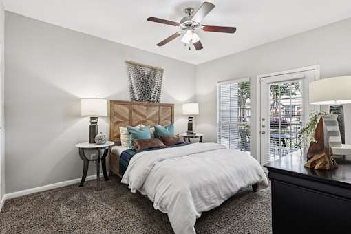 A bedroom with a large bed and a ceiling fan.