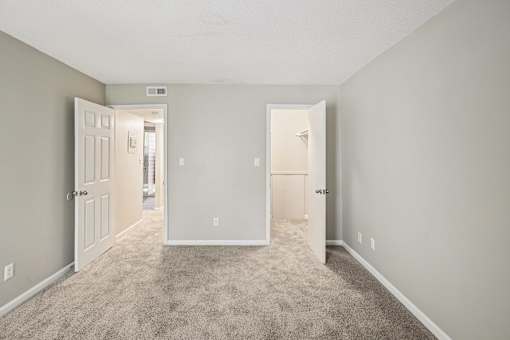 A room with carpeted floor and three doors.