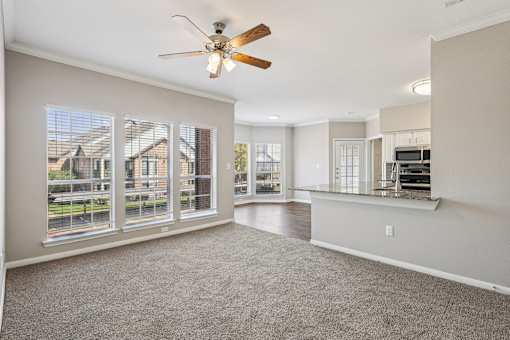 A spacious room with a ceiling fan and large windows.