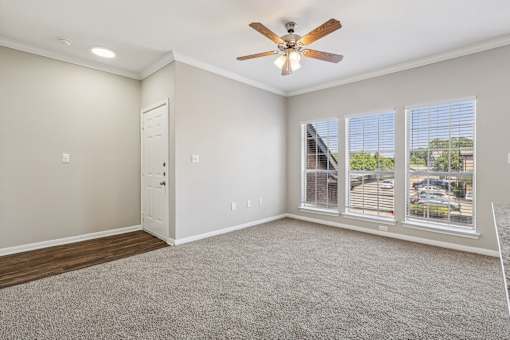 A room with a ceiling fan and carpeted floor.