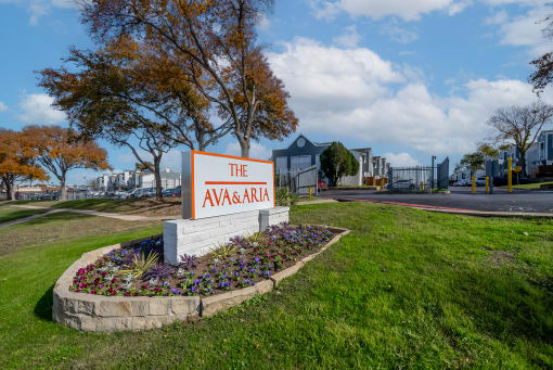 the avenue apartments sign in front of grass and flowers