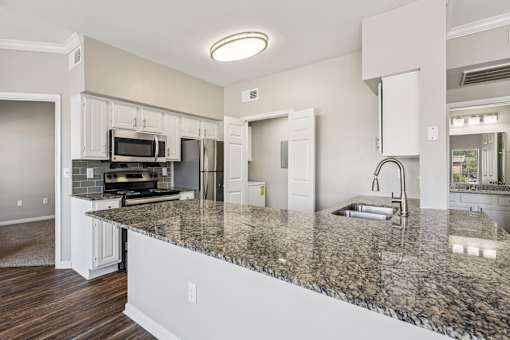A kitchen with granite countertops and white cabinets.