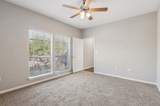 A room with a ceiling fan and a sliding glass door.