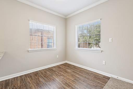 A room with wooden floors and two windows.
